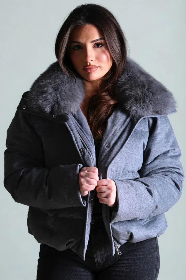 Woman wearing a gray coat with a fur collar against a light background