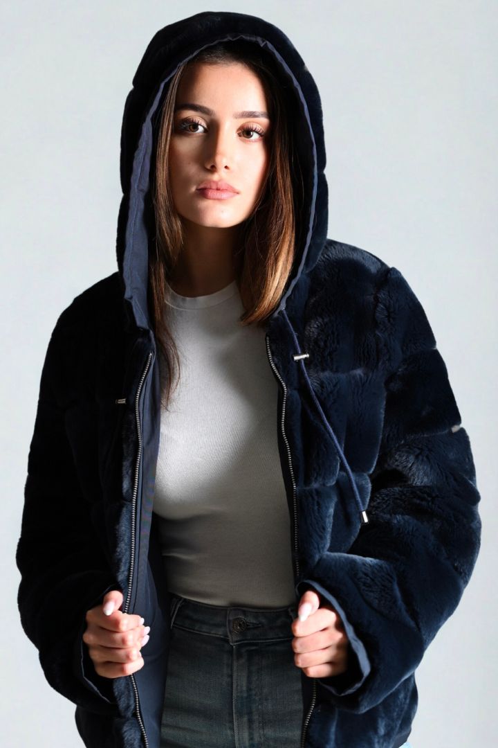 Woman wearing a dark blue hooded jacket against a plain background