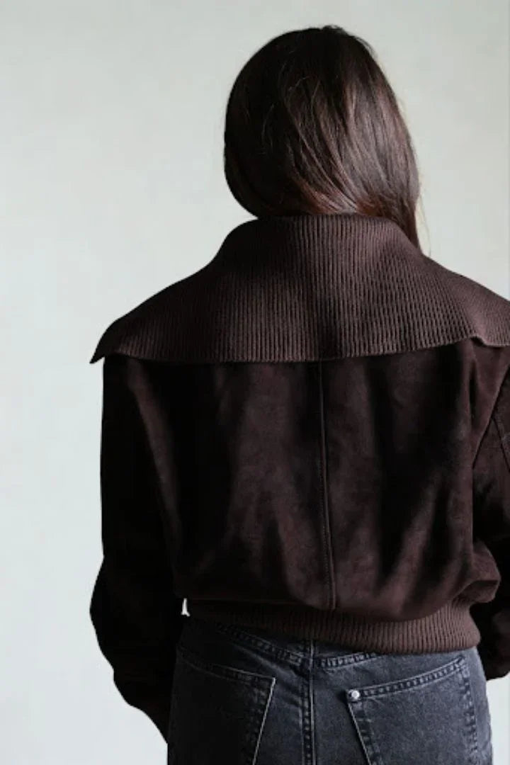 Back view of a woman wearing a dark brown suede jacket with a ribbed collar and hem.