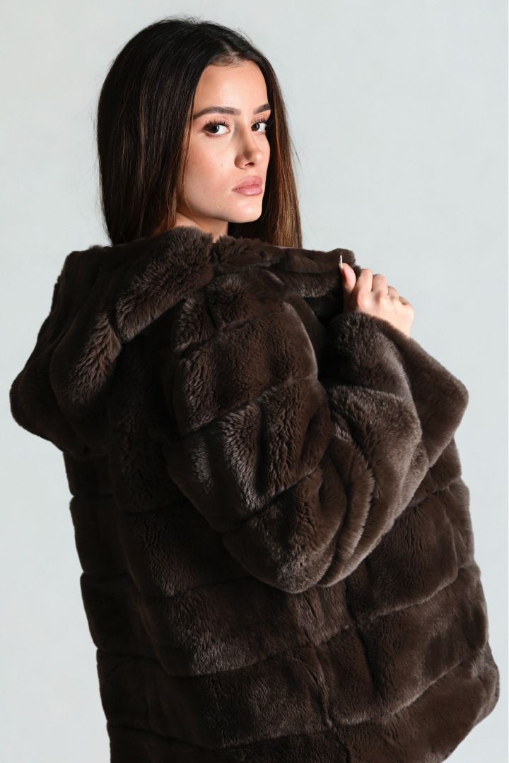 Woman wearing a brown fur coat against a plain background