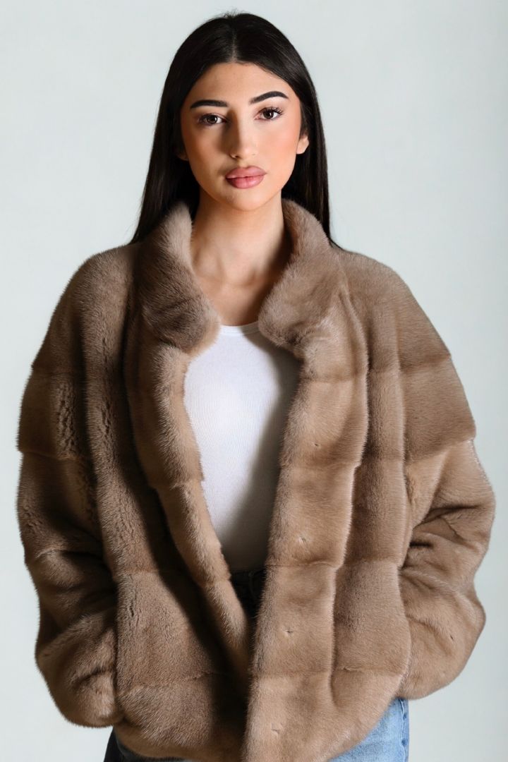 Woman wearing a brown fur coat against a plain background