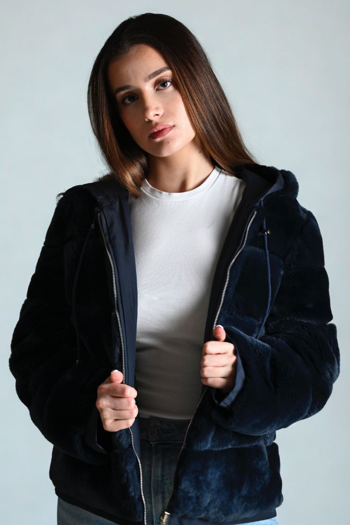 Woman wearing a dark blue jacket over a white shirt against a plain background
