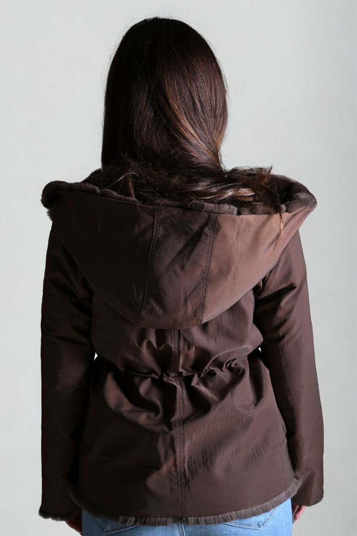 Brown jacket with fur hood worn by a person on a plain background