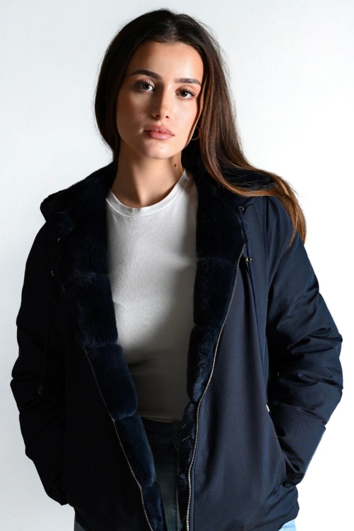 Woman wearing a navy blue jacket over a white shirt on a white background
