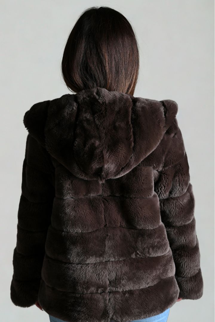 Brown fur coat with hood worn by a person on a plain background