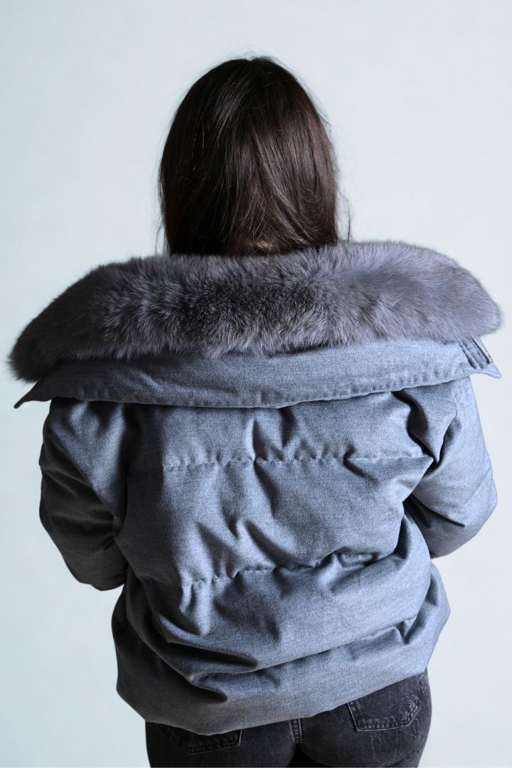 Person wearing a gray parka with a fur-lined hood against a white background