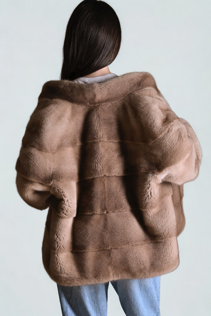 Brown fur coat worn by a person on a light gray background
